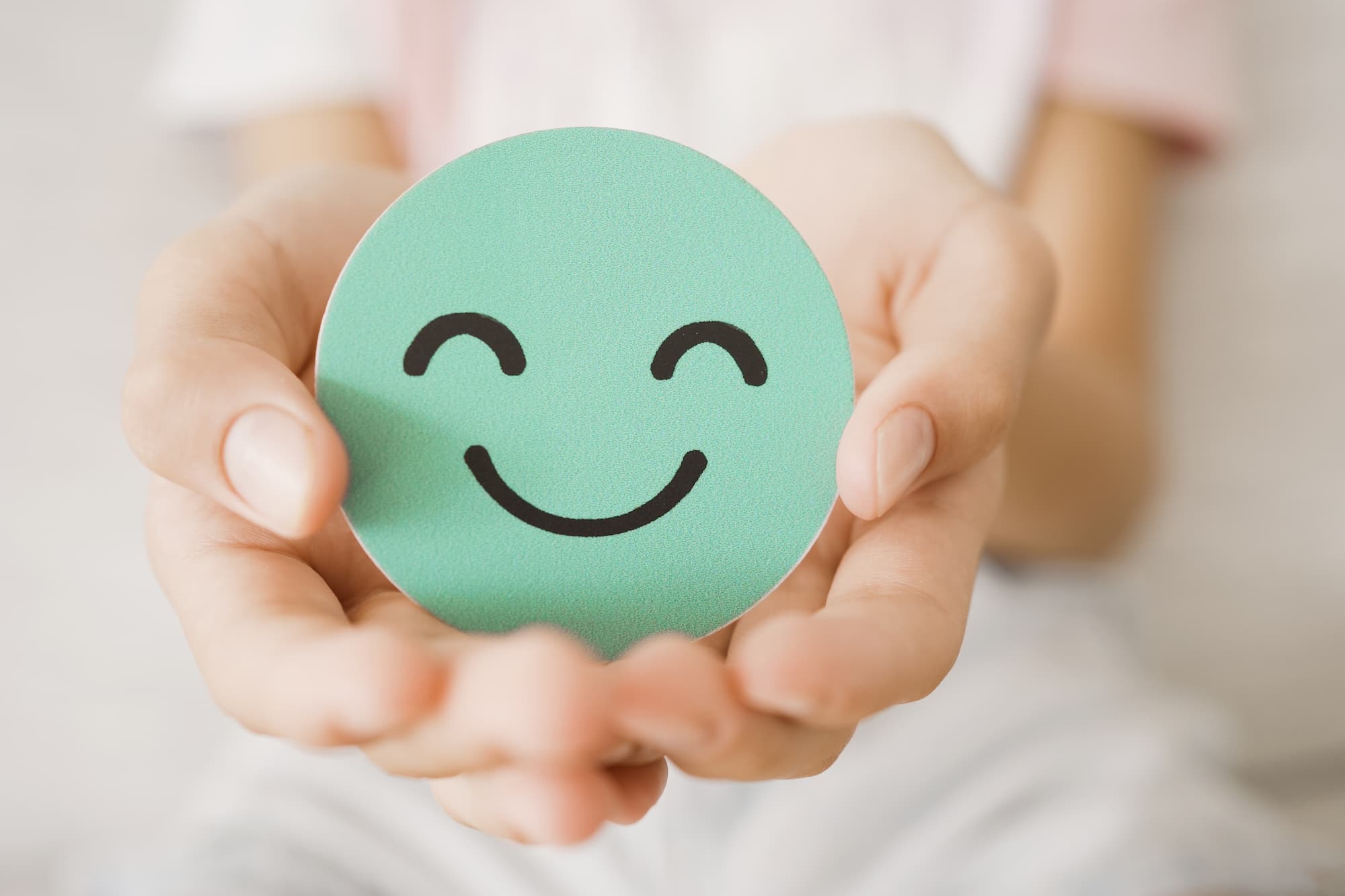 a hand holding a circular green smiley face