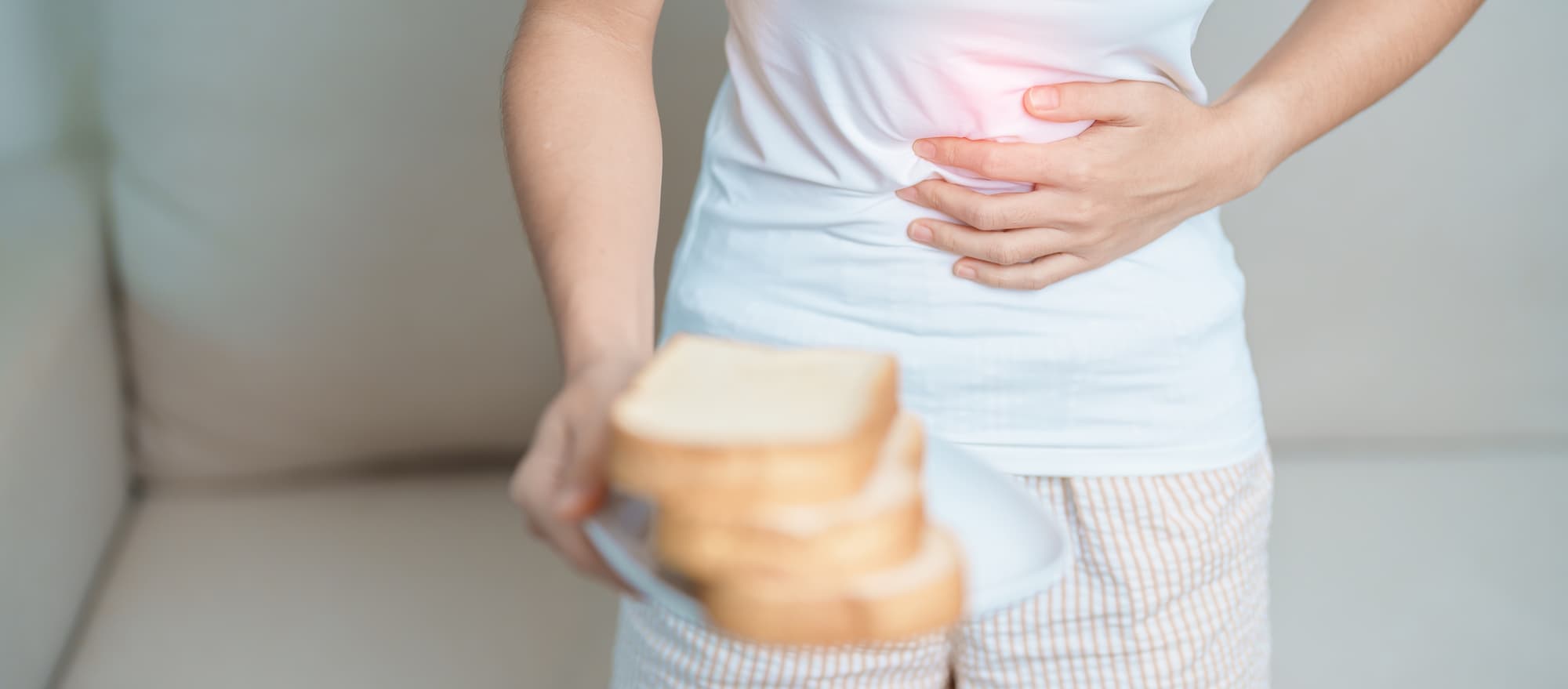 a person holding a plate of bread while holding their stomatch in pain a person holding a plate of bread while holding their stomatch in pain